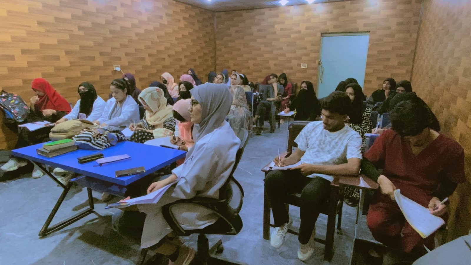 Male and female students taking notes during a classroom lecture at Agha Institute of Health Sciences, Lahore