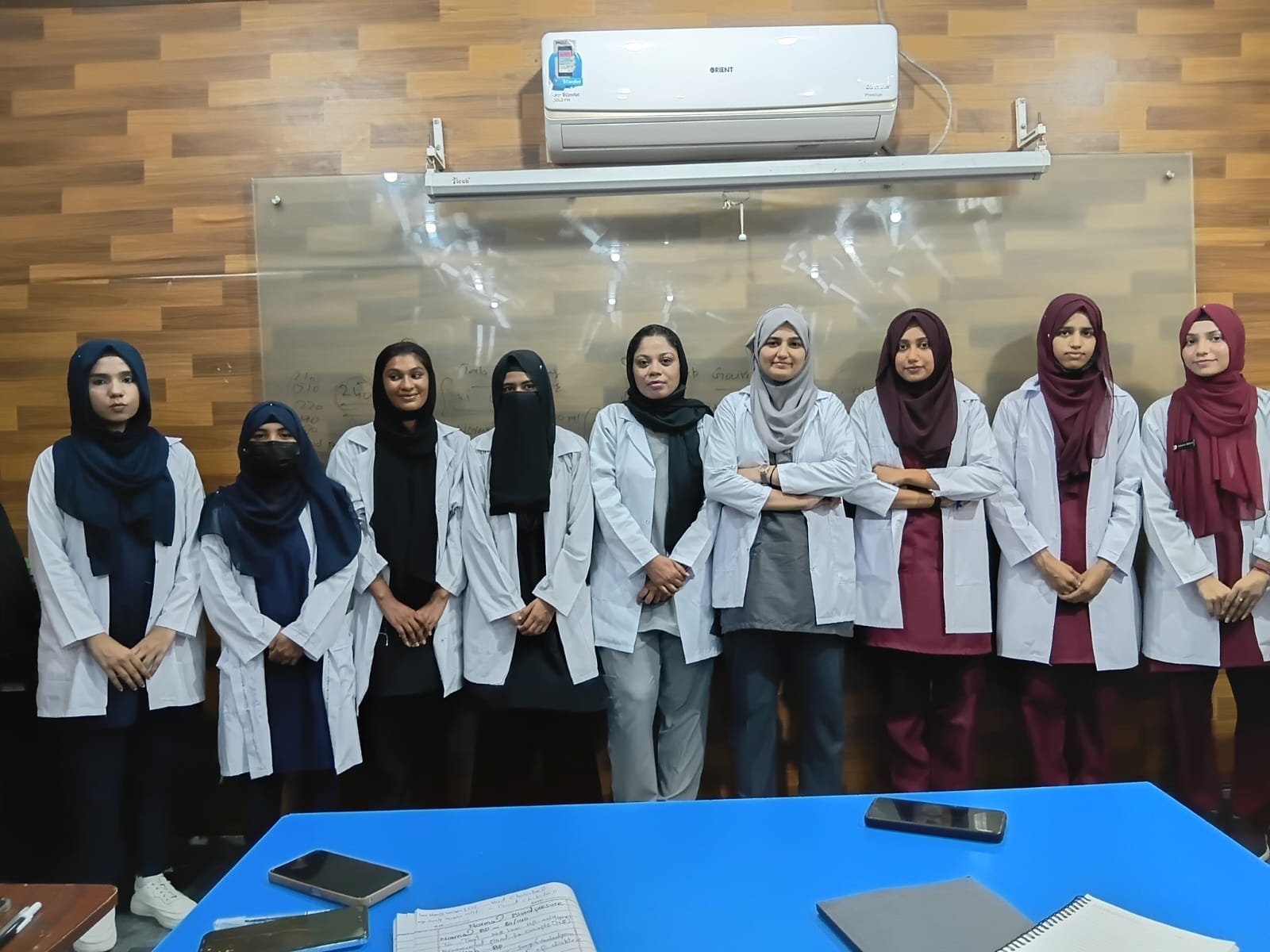 Nursing and allied health students in white lab coats standing together in a classroom at Agha Institute of Health Sciences, Lahore