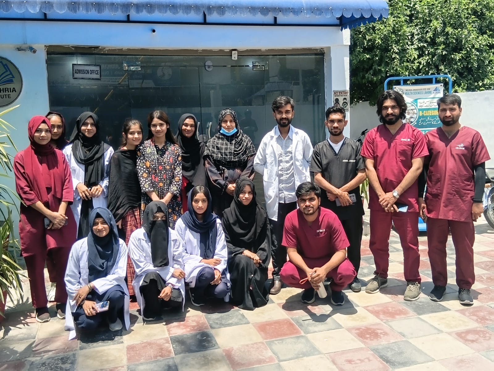 Students in scrubs and lab coats outside the admission office of Agha Institute of Health Sciences Lahore